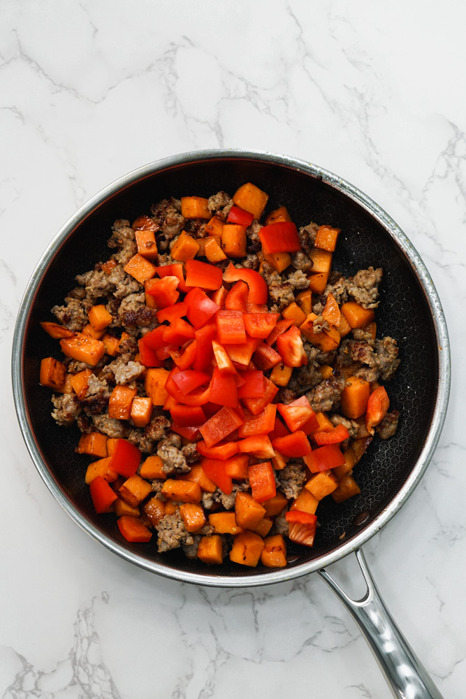 black pan with sausage, sweet potato and red bell pepper