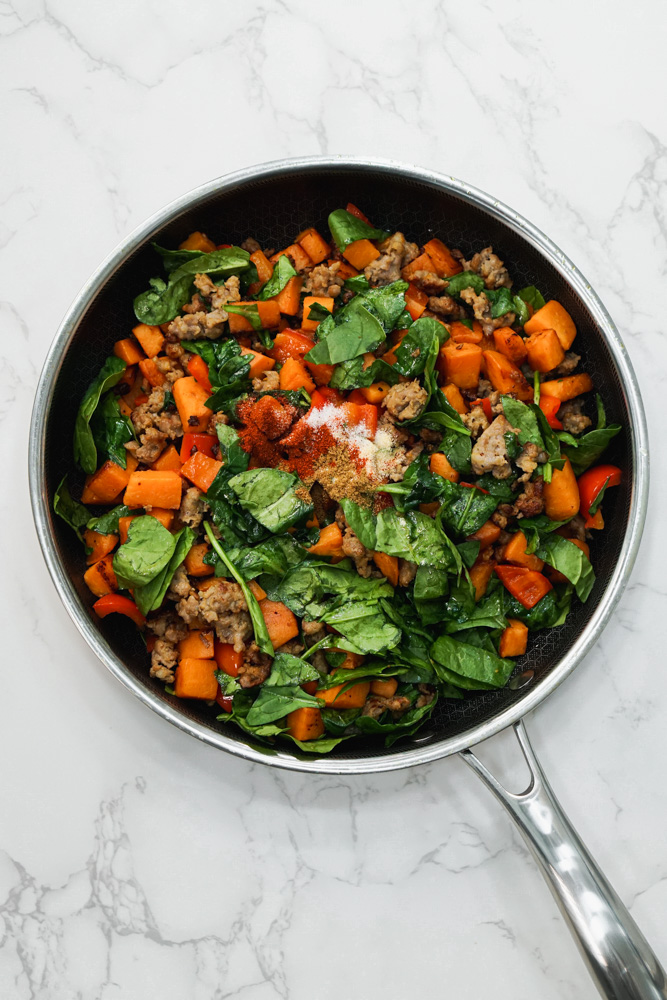 black pan with sausage, sweet potato, red bell pepper and spinach