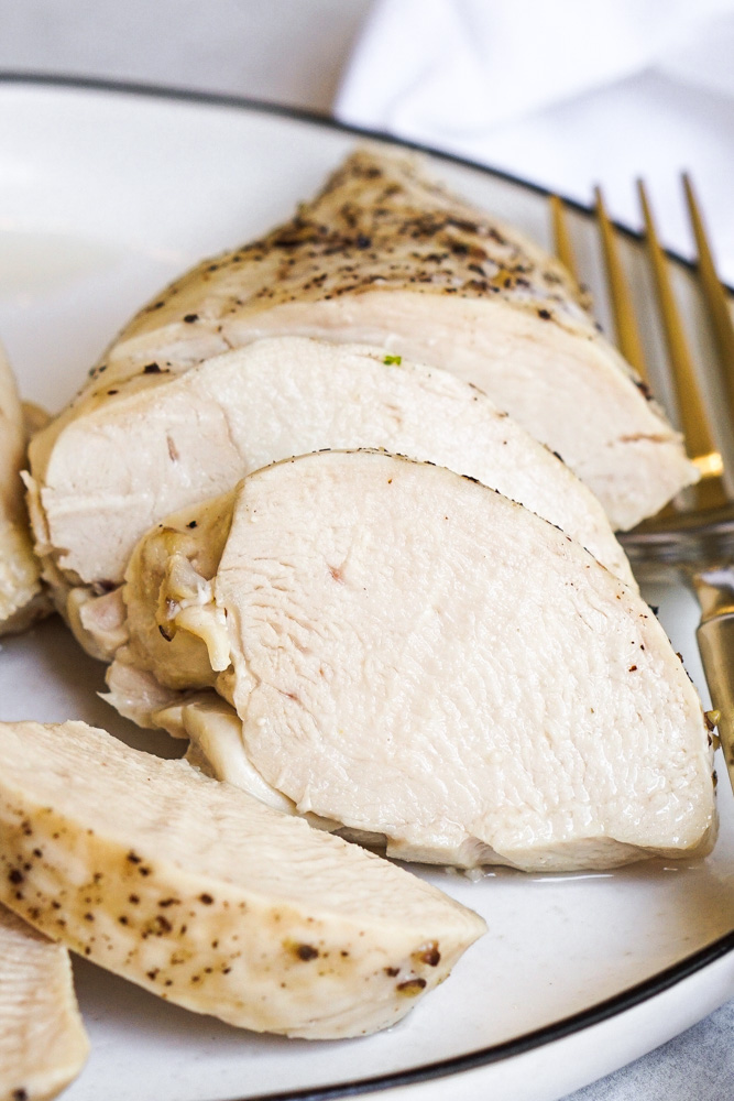 Sliced cooked chicken breast on white plate