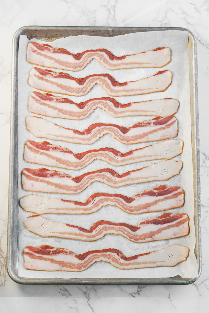 Raw bacon pieces on baking sheet